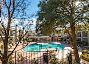 Thumbnail 7 of 21 - A pool surrounded by a fence with a tree in the foreground.