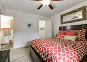 Thumbnail 17 of 21 - A bedroom with a patterned bedspread and a ceiling fan.