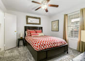 Thumbnail 18 of 21 - A bedroom with a bed, a ceiling fan, and a window with curtains.