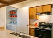 Thumbnail 3 of 21 - A kitchen with a black stove and wooden cabinets.