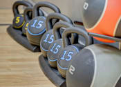 Thumbnail 20 of 27 - A set of kettlebells with weights of 5, 15, and 25 pounds are lined up on a wooden floor.