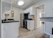 Thumbnail 6 of 27 - A kitchen with white cabinets and a black countertop.