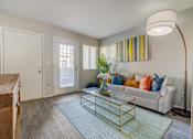 Thumbnail 3 of 27 - A living room with a white couch and a glass coffee table.