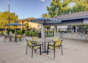 Thumbnail 22 of 27 - A patio with a table and chairs under an umbrella.