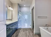 Thumbnail 16 of 31 - A modern bathroom with a white tub and wooden flooring.