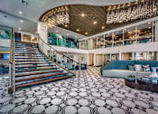 Thumbnail 17 of 31 - A large, open-concept living space with a staircase and a patterned floor.
