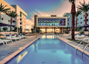 Thumbnail 22 of 31 - A large swimming pool surrounded by lounge chairs and palm trees.