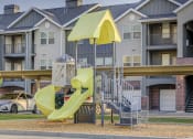 Thumbnail 19 of 33 - a playground with a yellow slide in front of an apartment building