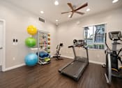 Thumbnail 13 of 31 - A room with a treadmill, exercise ball, and other fitness equipment.