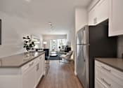 Thumbnail 20 of 31 - A modern kitchen with white cabinets and a black refrigerator.