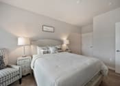 Thumbnail 22 of 31 - A bedroom with a large bed, a chair, and two lamps.