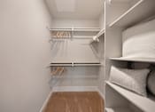 Thumbnail 25 of 31 - A walk-in closet with white shelves and hangers.