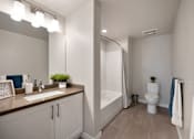 Thumbnail 28 of 31 - A bathroom with a sink, mirror, toilet, and bathtub.