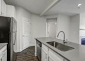 Thumbnail 42 of 45 - A kitchen with a black refrigerator and white cabinets.