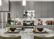 Thumbnail 3 of 34 - A modern kitchen with a stainless steel refrigerator and a center island with two bowls on top.