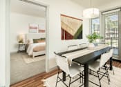 Thumbnail 4 of 34 - A dining table with four chairs is in the foreground of a room with a bed in the background.