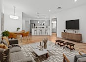 Thumbnail 6 of 34 - A modern living room with a grey sofa, wooden coffee table, and a television.