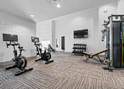 Thumbnail 18 of 34 - A gym with a row of stationary bikes and a squat rack.