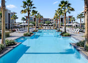 Thumbnail 19 of 34 - A long rectangular pool surrounded by palm trees and lounge chairs.