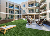 Thumbnail 23 of 34 - A patio with a table and chairs is surrounded by apartment buildings.