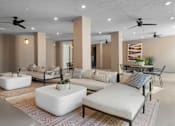Thumbnail 24 of 34 - A living room with a white sofa, a white coffee table, and a rug with a geometric pattern.