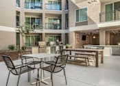Thumbnail 26 of 34 - A patio with a table and chairs is surrounded by apartment buildings.