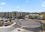 Thumbnail 32 of 34 - A roundabout in front of apartment buildings with cars parked on the side.