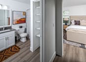 Thumbnail 8 of 23 - A white bathroom with a toilet, sink, and a bedroom with a bed.
