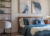 Thumbnail 8 of 34 - A bedroom with a bed, chair, and two paintings on the wall.