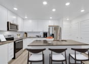 Thumbnail 48 of 51 - a kitchen with white cabinets and a large island with three chairs