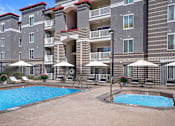 Thumbnail 21 of 29 - A large swimming pool surrounded by lounge chairs and umbrellas in front of a multi-story apartment building.