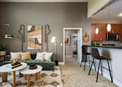 Thumbnail 16 of 24 - a living room with a couch and a kitchen with a bar