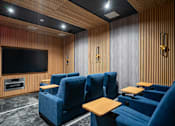 Thumbnail 9 of 24 - a cinema room with blue chairs and a television
