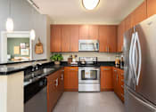 Thumbnail 18 of 24 - a modern kitchen with stainless steel appliances and wooden cabinets