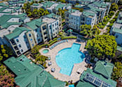 Thumbnail 29 of 31 - An aerial view of apartment buildings surrounding a swimming pool.