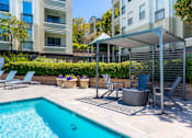 Thumbnail 27 of 31 - A pool with a hot tub and chairs under a canopy.