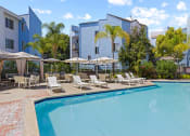 Thumbnail 10 of 53 - a swimming pool with lounge chairs and umbrellas in front of a building at Enclave, Paramount California