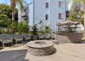 Thumbnail 16 of 53 - a fire pit with chairs and umbrellas in front of a white building at Enclave, Paramount California