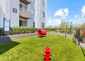 Thumbnail 21 of 53 - a red fire hydrant sitting on top of a lush green field at Enclave, Paramount