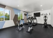 Thumbnail 27 of 53 - a room filled with lots of exercise equipment and a flat screen tv at Enclave, Paramount, CA