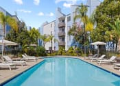Thumbnail 8 of 53 - a swimming pool with chaise lounge chairs and umbrellas in front of an apartment building at Enclave, California, 90723
