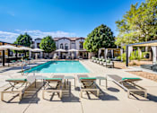 Thumbnail 2 of 38 - a swimming pool with chairs and umbrellas and a building in the background