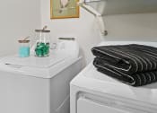 Thumbnail 13 of 36 - a white washer and dryer in a bathroom with a stack of black towels