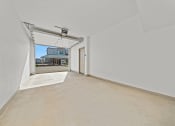Thumbnail 14 of 36 - a spacious living room with white walls and a door to a parking garage