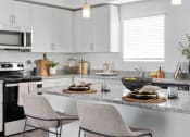 Thumbnail 2 of 36 - a kitchen with white cabinets and granite counter tops and a table with chairs