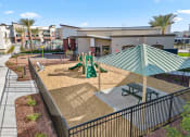 Thumbnail 32 of 36 - a playground with a picnic table and benches in front of a building