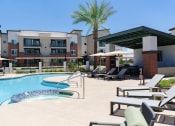 Thumbnail 20 of 36 - a swimming pool with chairs and umbrellas in front of an apartment building