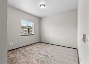 Thumbnail 26 of 50 - A room with a carpeted floor and a window showing a building outside.