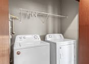 Thumbnail 27 of 50 - A white washing machine and dryer in a small laundry room.