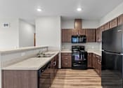 Thumbnail 18 of 50 - A modern kitchen with dark wood cabinets and black appliances.